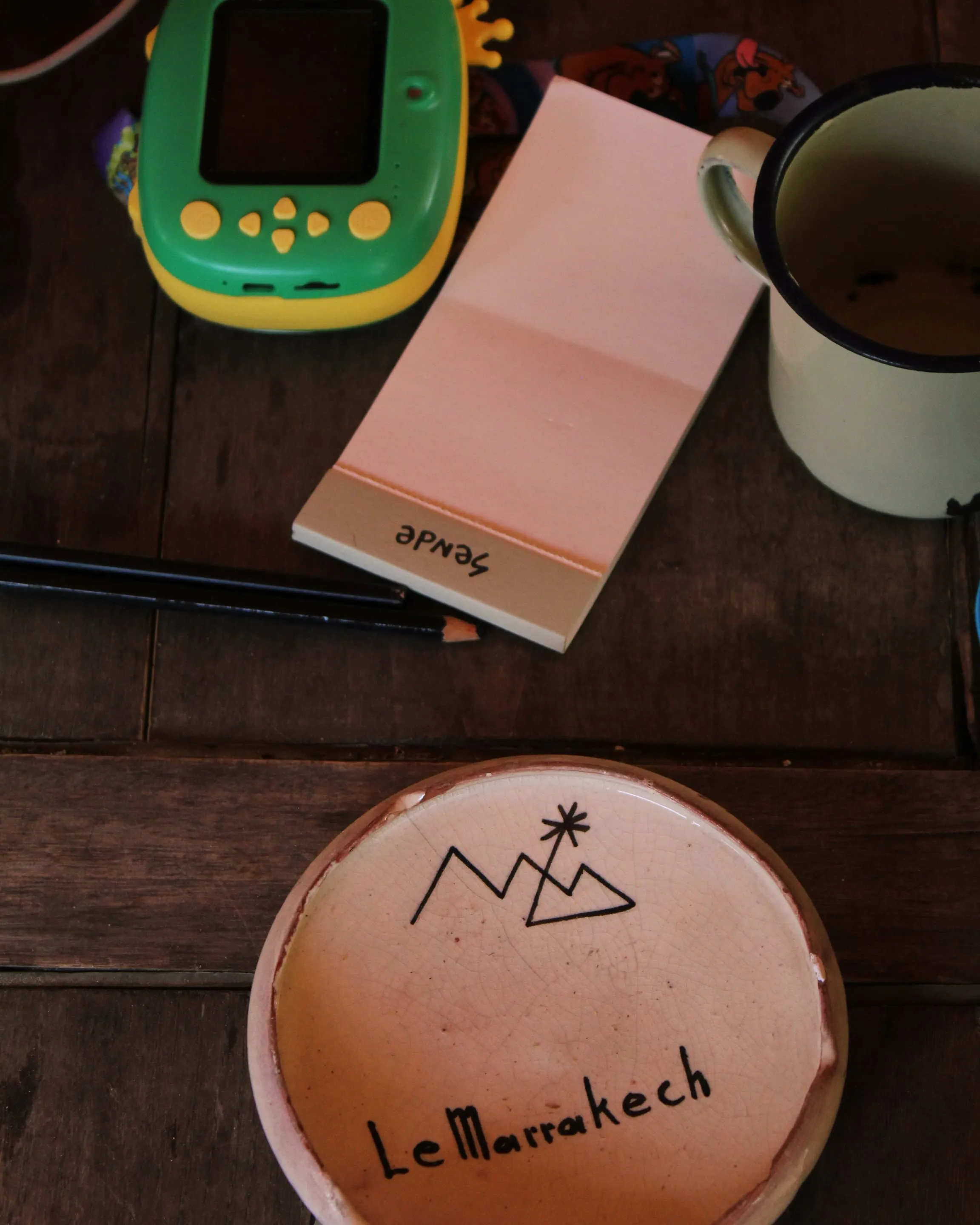 Consola portátil, libreta de Sende y taza sobre una mesa de madera