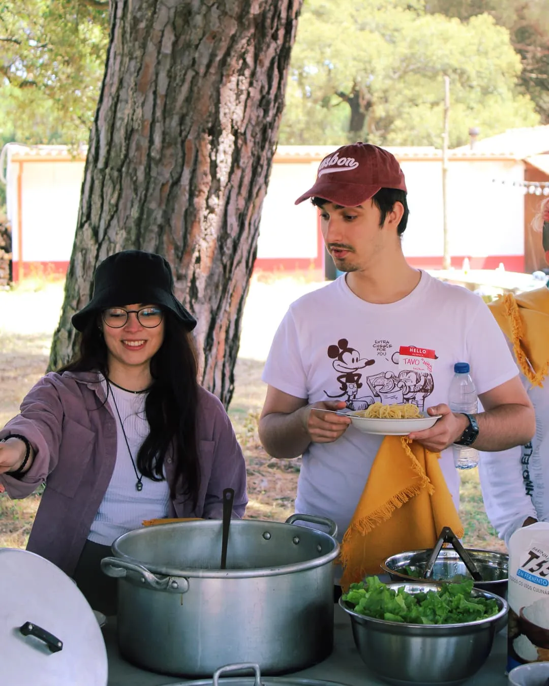 Dos personas sirviendo comida en la cocina del campamento